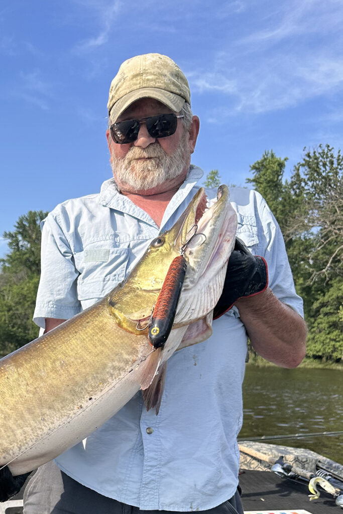 Portrait of Tom catching a musky with the Walk of Death in Orange Crush color